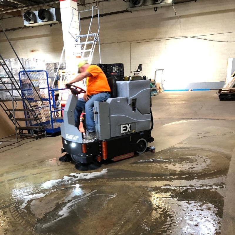 Tomcat Ride On Floor Scrubbers EX warehouse concrete A Tomcat EX ride on battery floor scrubber cleans the concrete floor of a food distributor warehouse in Dayton, OH