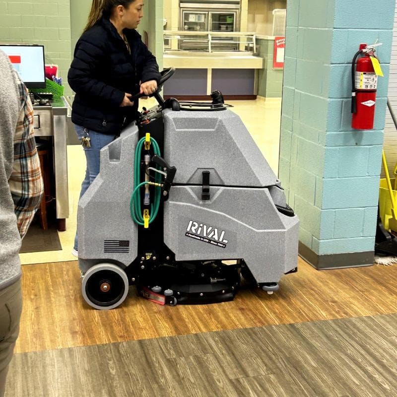 Tomcat Stand On Floor Scrubbers Rival cafeteria vinyl plank A Tomcat Rival stand on battery floor scrubber cleaning the luxury vinyl tile (LVT) floor of a school cafeteria in Austin, TX