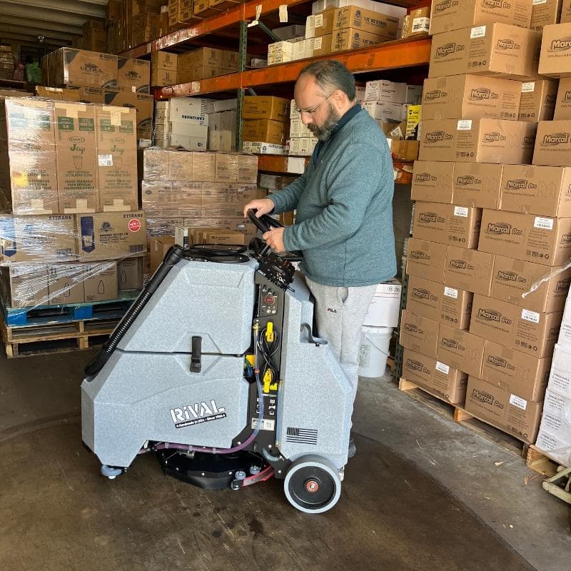 Tomcat Stand On Floor Scrubbers Rival warehouse concrete A Tomcat Rival Stand On Floor Scrubber demonstrates how maneuverable it is, in a crowded warehouse in South Florida.